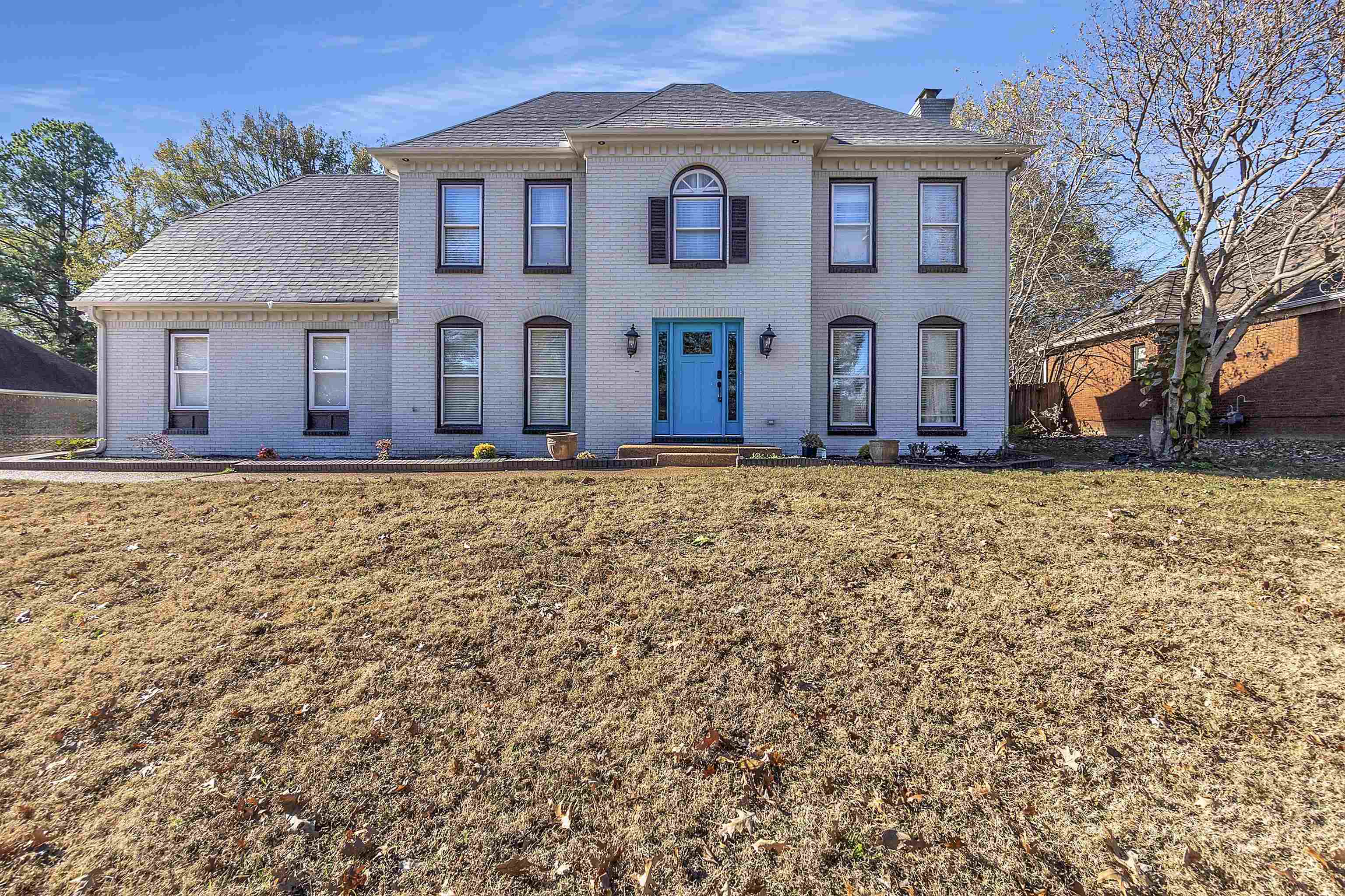 View of front of house with brick siding, a chimney, and a front lawn