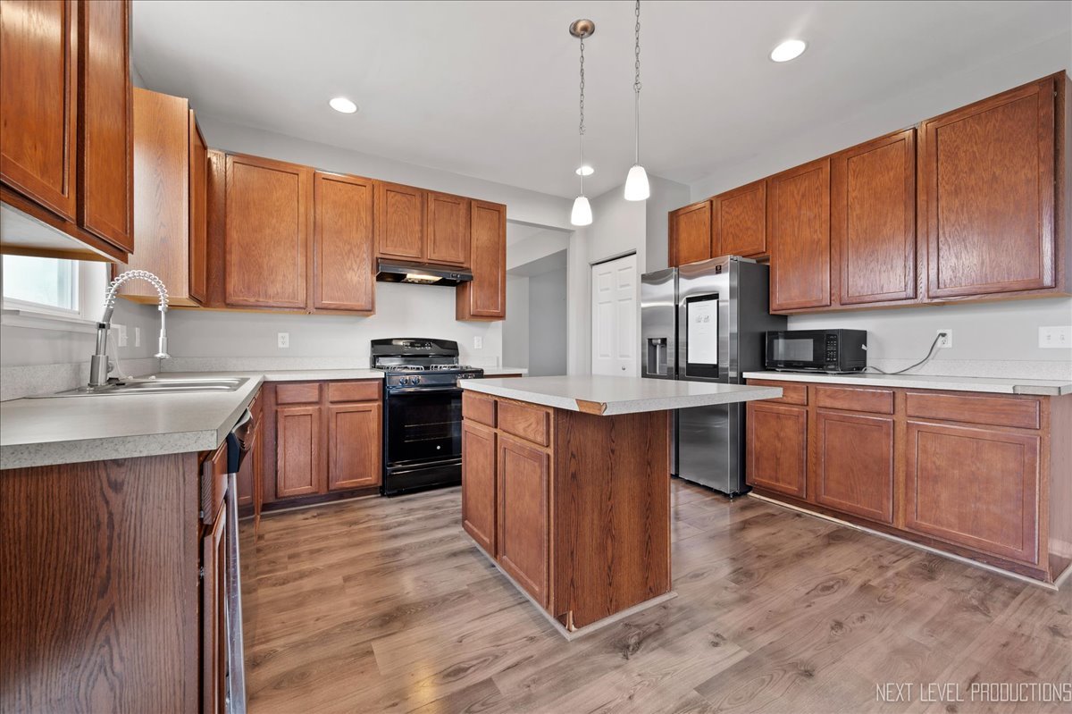 442 Windett Ridge Road Yorkville, IL 60560 - Photo 16 of 43 a kitchen with kitchen island granite countertop wooden cabinets stainless steel appliances a sink and a center island