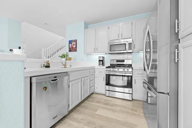 a kitchen with white cabinets and stainless steel appliances