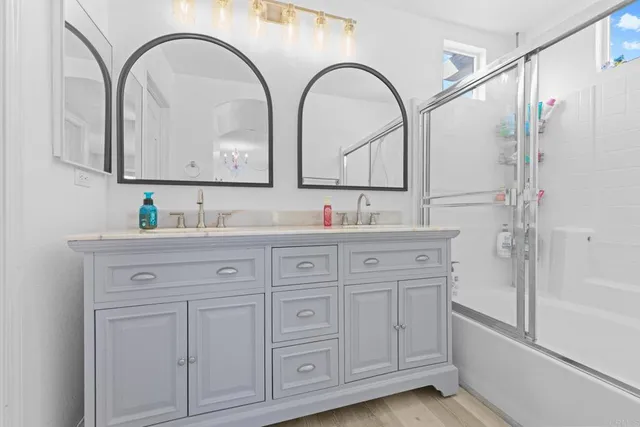 a bathroom with a granite countertop sink a mirror a vanity and the shower