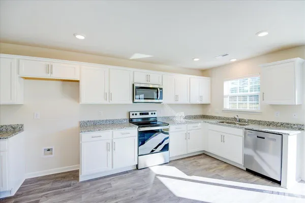 a kitchen with stainless steel appliances granite countertop a stove and white cabinets