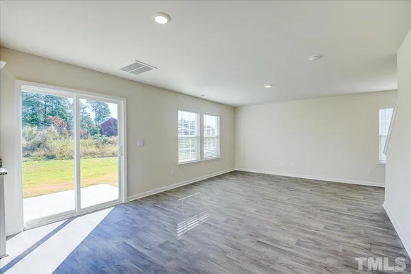 a view of an empty room with wooden floor and closet