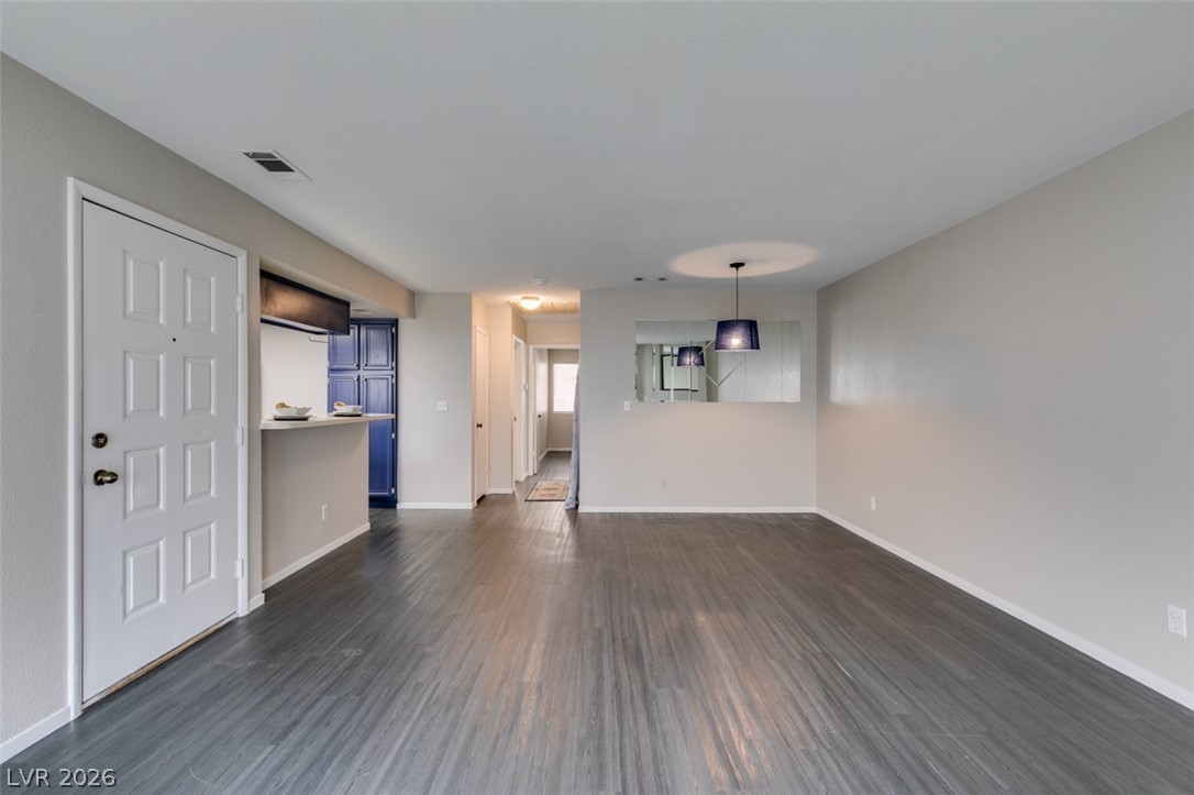 810 North Sloan Lane, Unit 103 Las Vegas, NV 89110 - Photo 3 of 16 Unfurnished living room featuring dark wood-style floors and baseboards