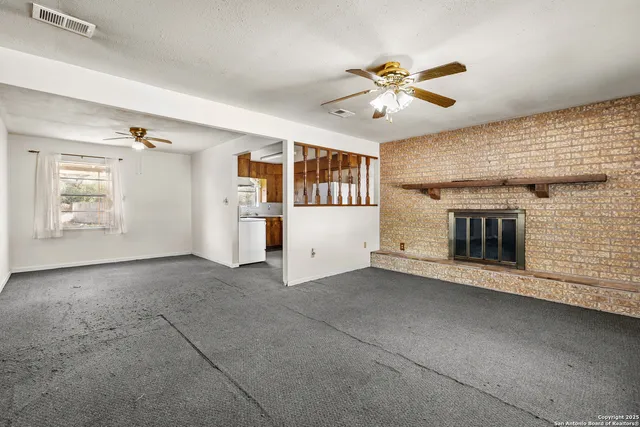 an empty room with windows and ceiling fan