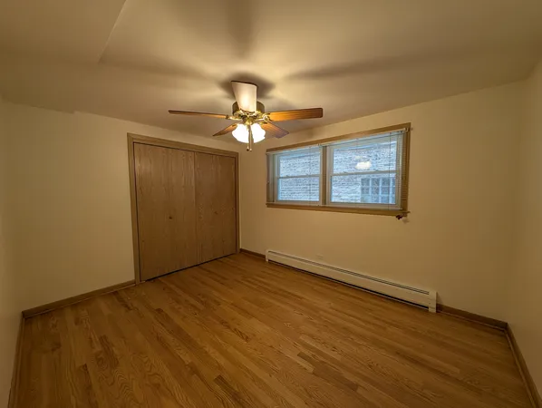 an empty room with wooden floor chandelier fan and windows