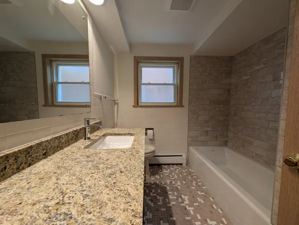 a bathroom with a granite countertop sink a mirror and a bathtub