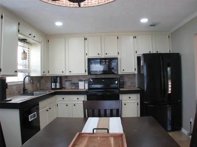 a kitchen with a sink a refrigerator and cabinets