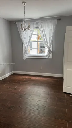 a view of empty room with window and chandelier fan