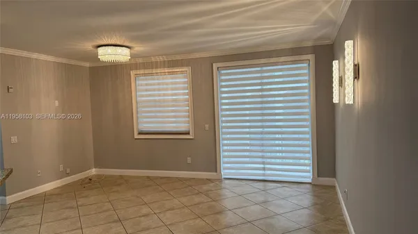 a view of an empty room with window and chandelier fan
