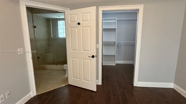an empty room with wooden floor closet and windows