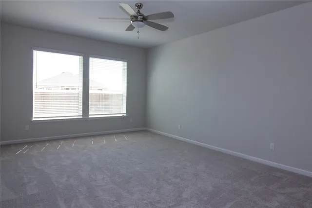 an empty room with ceiling fan and windows