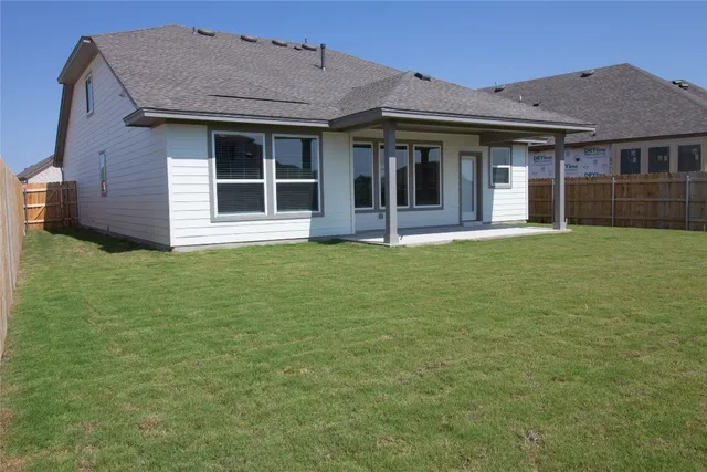 a view of a white house with a large window potted plants and large tree