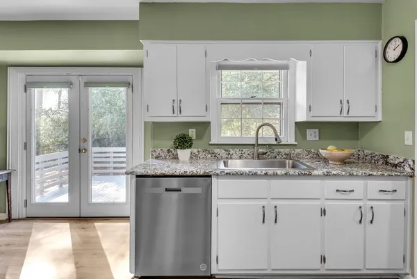 a kitchen with stainless steel appliances granite countertop a refrigerator a sink dishwasher a stove and white countertops with wooden floor