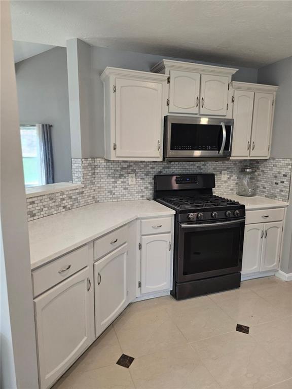 6992 Ivy Pointe Row Austell, GA 30168 - Photo 18 of 32 a kitchen with granite countertop white cabinets and stainless steel appliances
