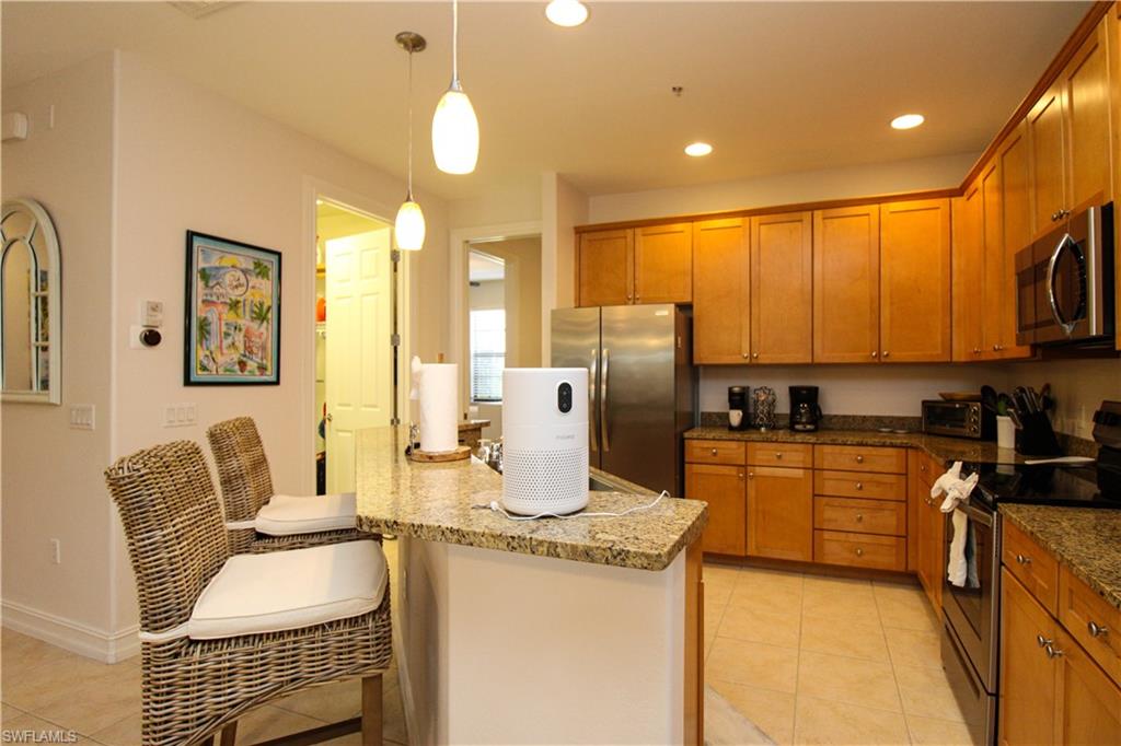 9159 Delano Street, Unit 9905 Naples, FL 34113 - Photo 12 of 44 a kitchen with stainless steel appliances granite countertop a stove top oven a sink dishwasher a dining table and chairs with wooden floor