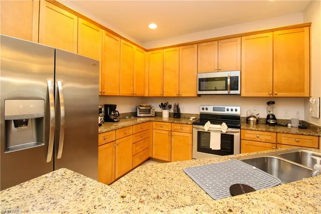 a kitchen with stainless steel appliances granite countertop a refrigerator a stove a sink and a microwave