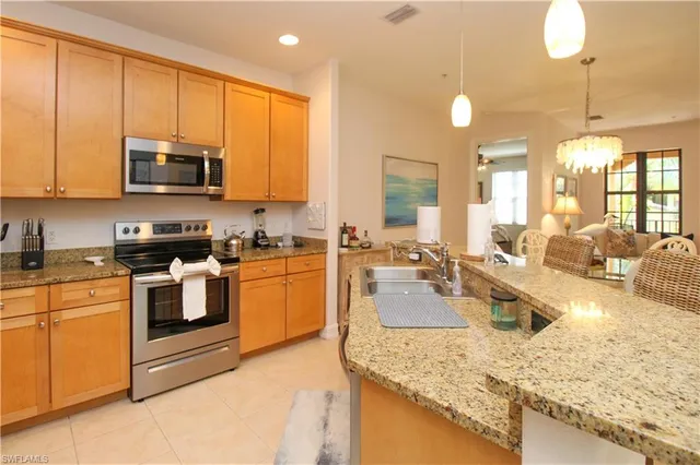 a kitchen with kitchen island granite countertop a sink counter top space appliances and cabinets