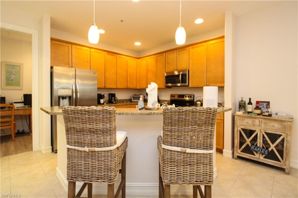 9159 Delano Street, Unit 9905 Naples, FL 34113 - Photo 16 of 44 a kitchen with stainless steel appliances kitchen island granite countertop a stove and a sink