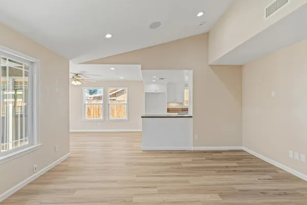 a view of an empty room with wooden floor and a window