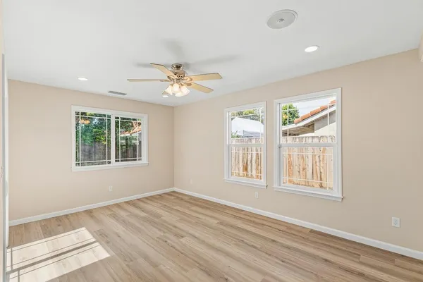 a view of an empty room with a window and wooden floor