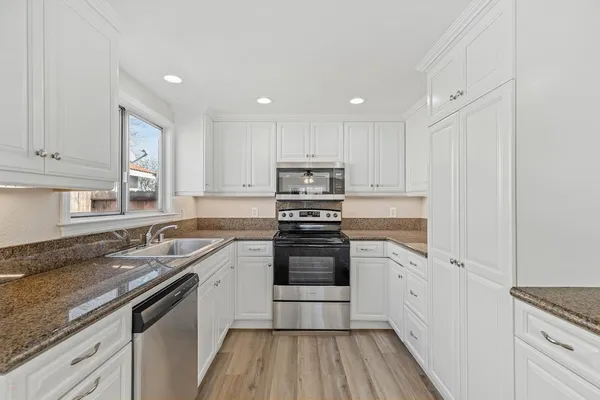 a kitchen with stainless steel appliances granite countertop a stove and white cabinets
