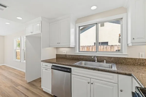 a kitchen with granite countertop a sink appliances cabinets and a large window