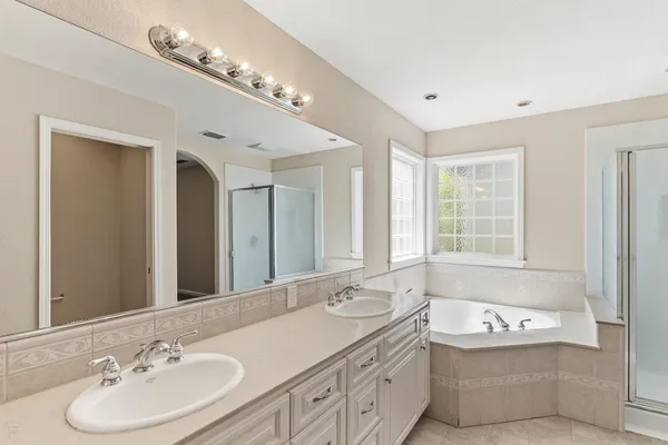 a bathroom with a bathtub a double vanity sink and a mirror