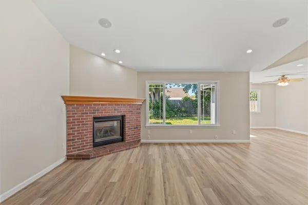 an empty room with wooden floor fireplace and windows
