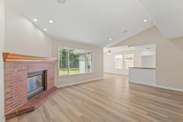 a view of empty room with wooden floor and fireplace