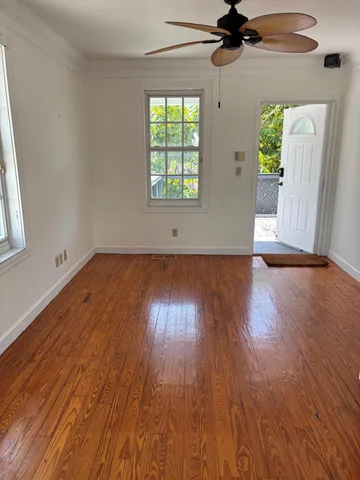 a view of an empty room with wooden floor and a window