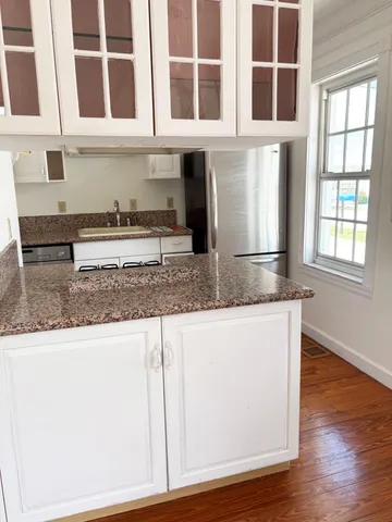 a kitchen with granite countertop a stove and a white wooden cabinets