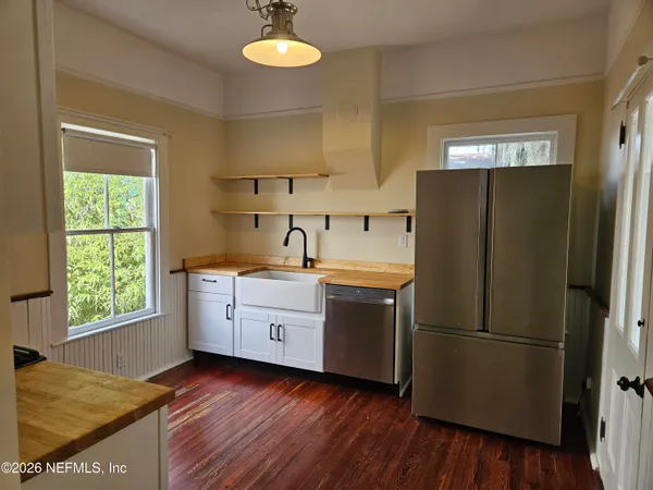 a kitchen with stainless steel appliances granite countertop a refrigerator a sink and white cabinets
