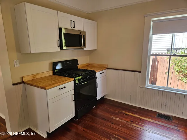 a kitchen with granite countertop a stove and a wooden floor