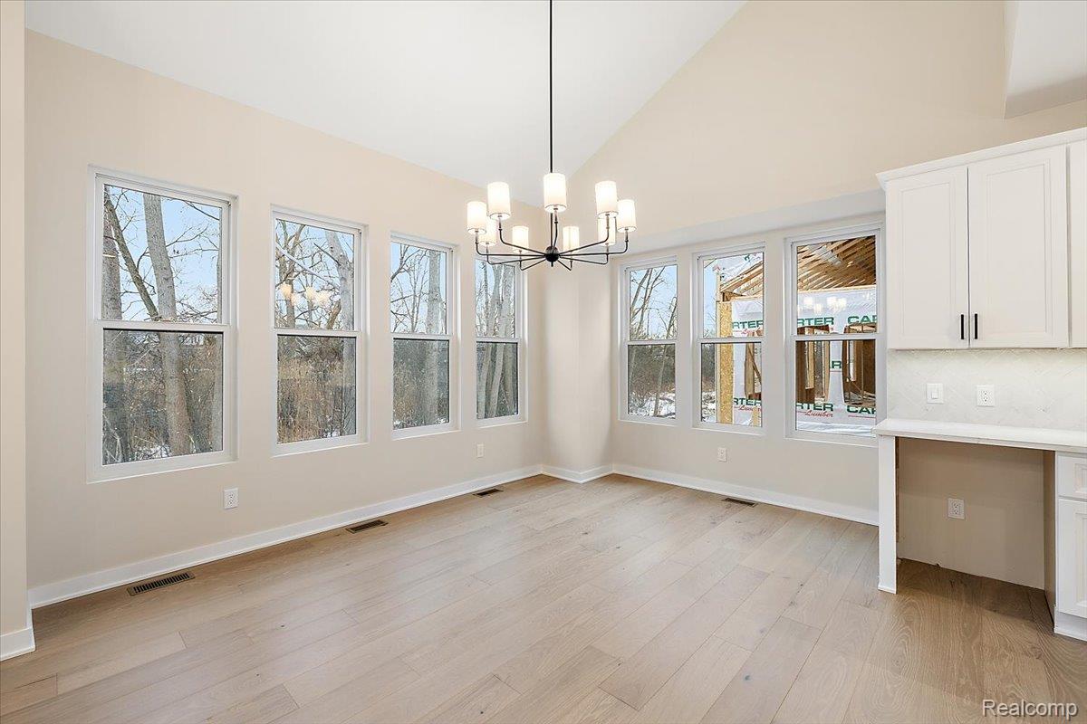 2044 Breckenridge Court Rochester, MI 48309 - Photo 13 of 33 Unfurnished dining area featuring light wood-style flooring, a chandelier, and high vaulted ceiling
