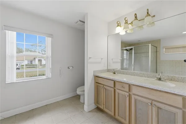 a bathroom with a granite countertop double vanity sink and a mirror