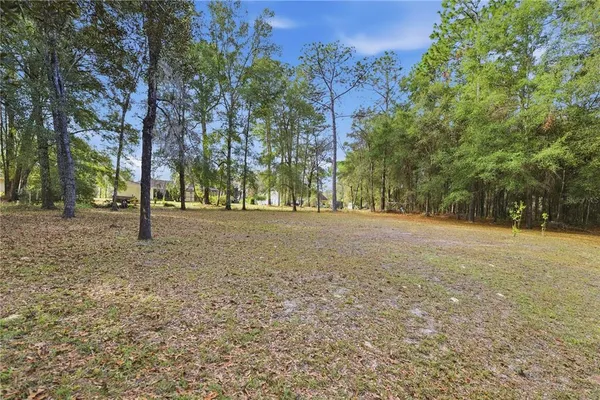 an aerial view of residential house with outdoor space and trees all around