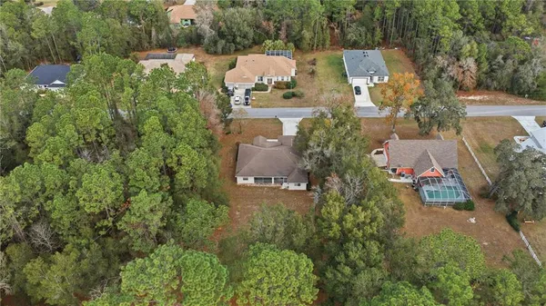 an aerial view of residential house with outdoor space and trees all around