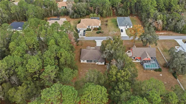 an aerial view of residential house with outdoor space and trees all around