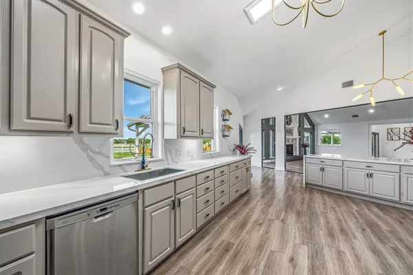 a large kitchen with stainless steel appliances granite countertop a lot of counter space and wooden floors