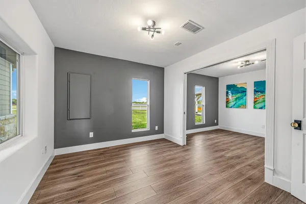 a view of an empty room with window and wooden floor