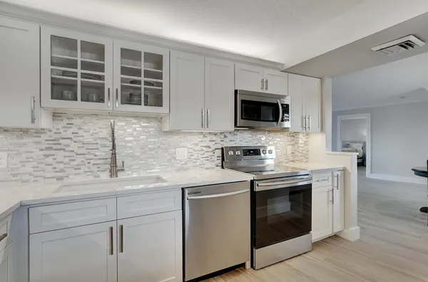 a kitchen with stainless steel appliances granite countertop white cabinets and a stove top oven