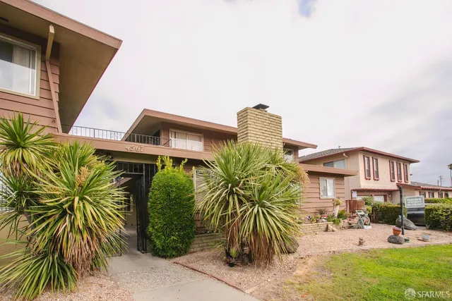 a palm tree sitting in front of a house with a yard