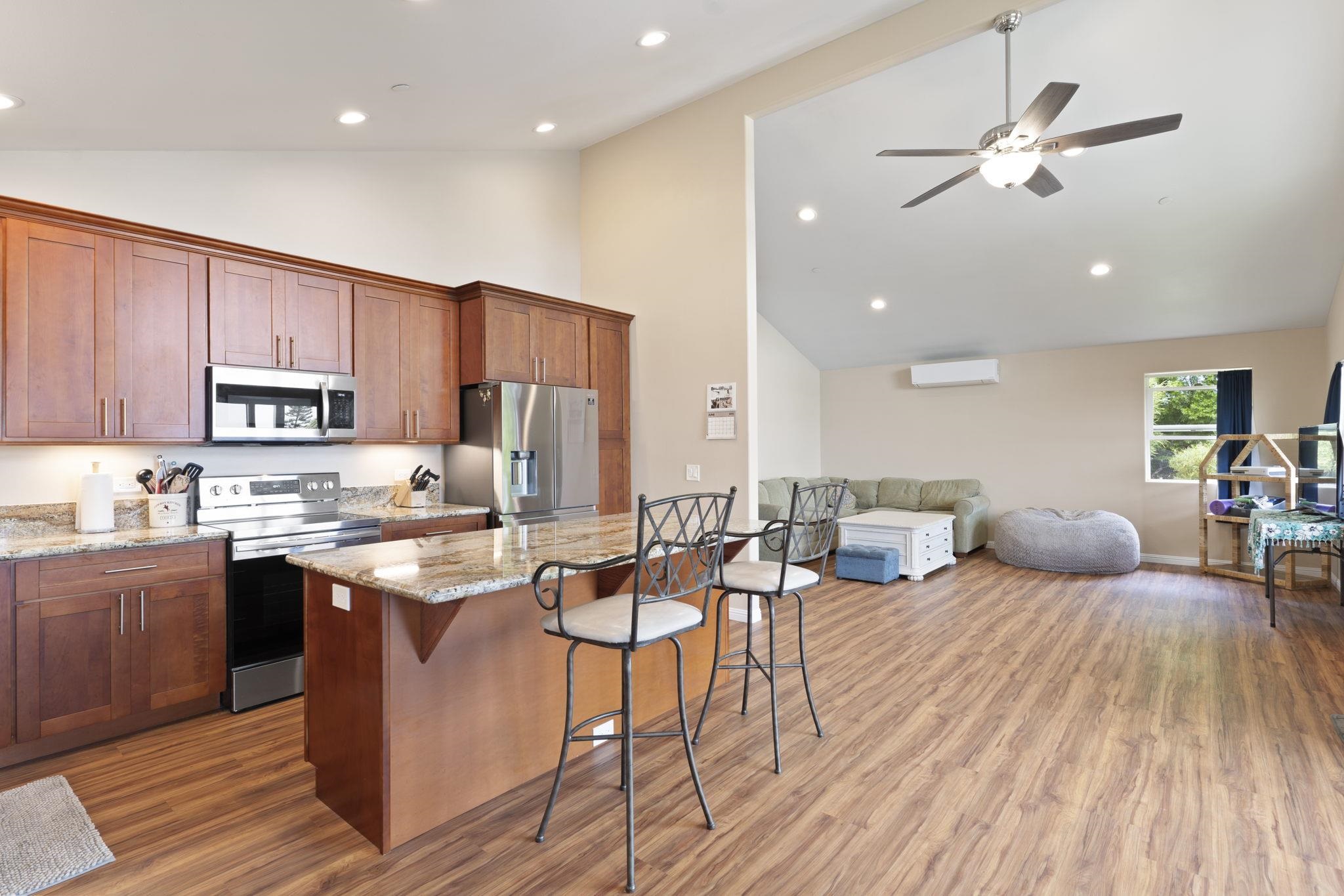 752 Awalau Road, Unit B Haiku, HI 96708 - Photo 7 of 30 a kitchen with stainless steel appliances kitchen island granite countertop a table chairs and a refrigerator