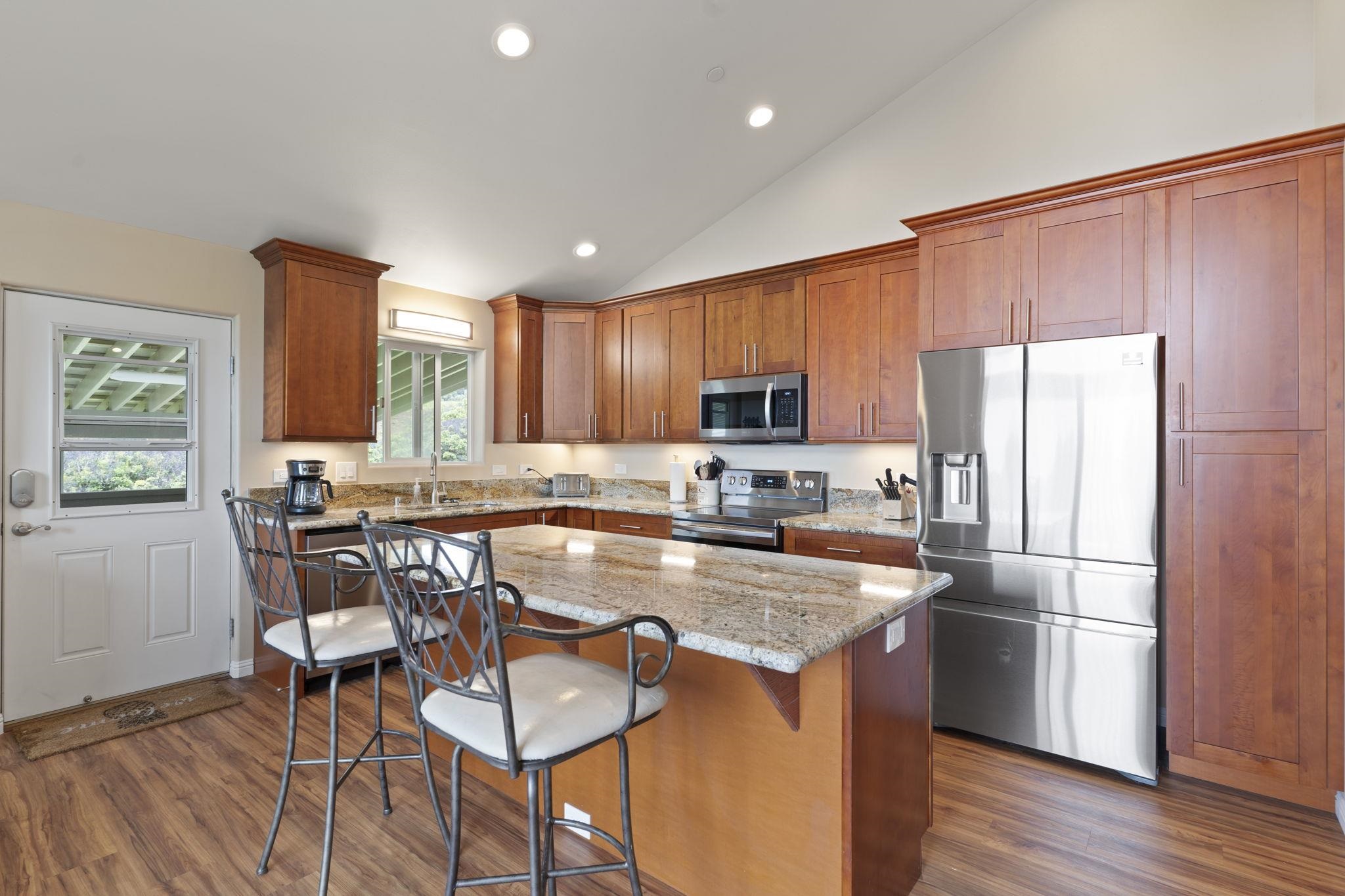 752 Awalau Road, Unit B Haiku, HI 96708 - Photo 10 of 30 a kitchen with granite countertop a refrigerator a stove a sink a dining table and chairs with wooden floor