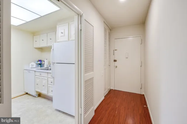 a view of a hallway with wooden floor and a bathroom