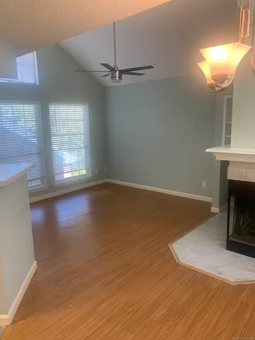 an empty room with wooden floor fireplace and windows