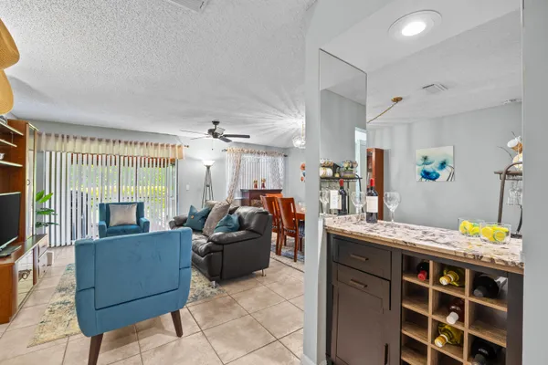 a living room with furniture a flat screen tv and a refrigerator