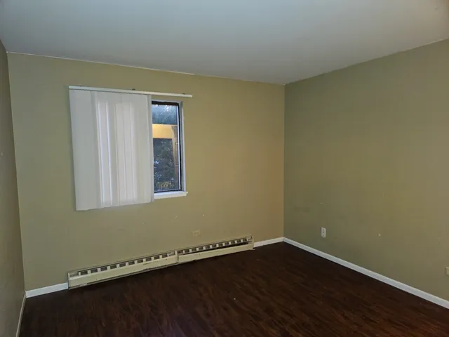 an empty room with a wooden floor and windows