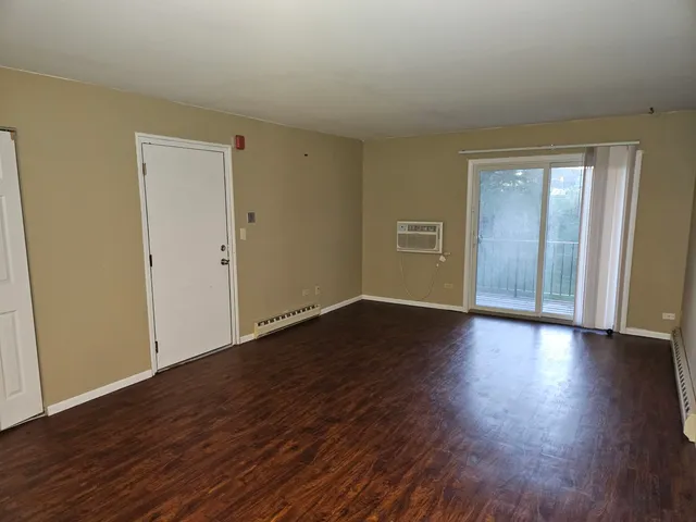 a view of an empty room with wooden floor and closet