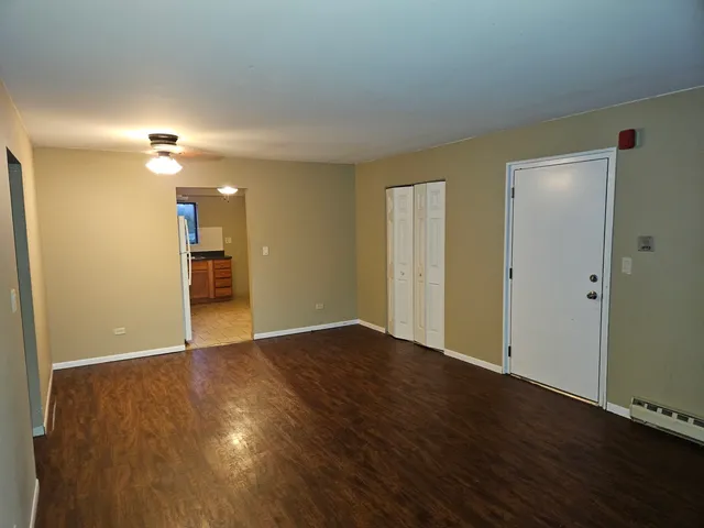 an empty room with wooden floor and a ceiling fan